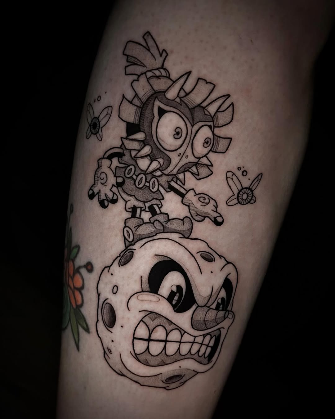 Cartoon Majora's Mask above a grinning skull tattoo