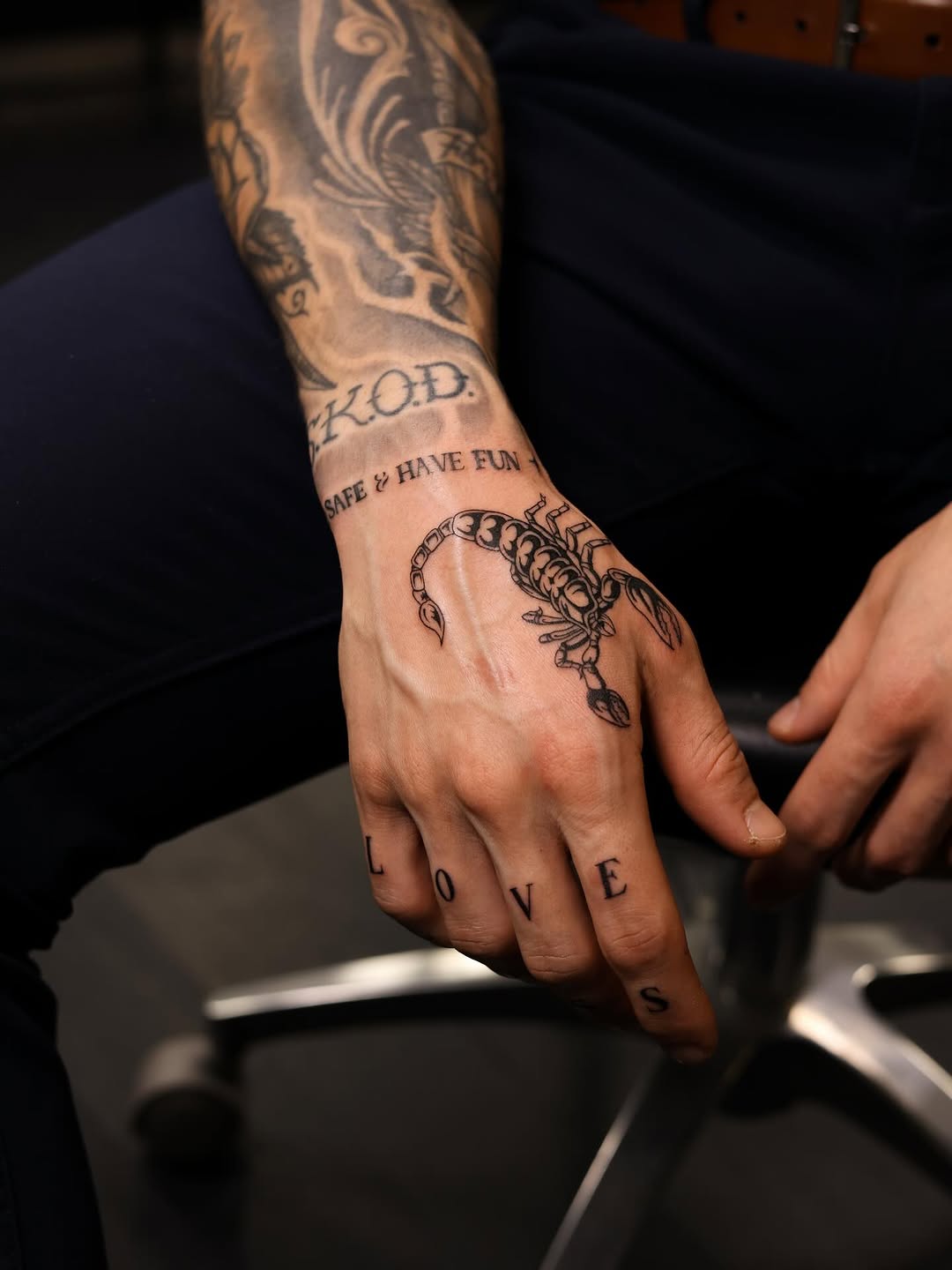 Bold blackwork scorpion with knuckle lettering spelling LOVE