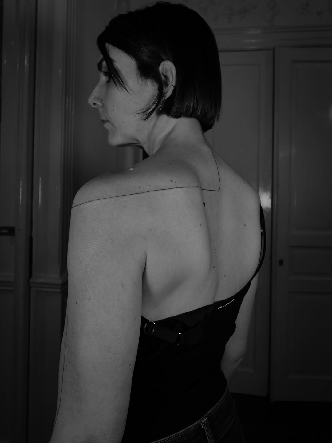 Delicate straight-line tattoo tracing shoulder to upper back