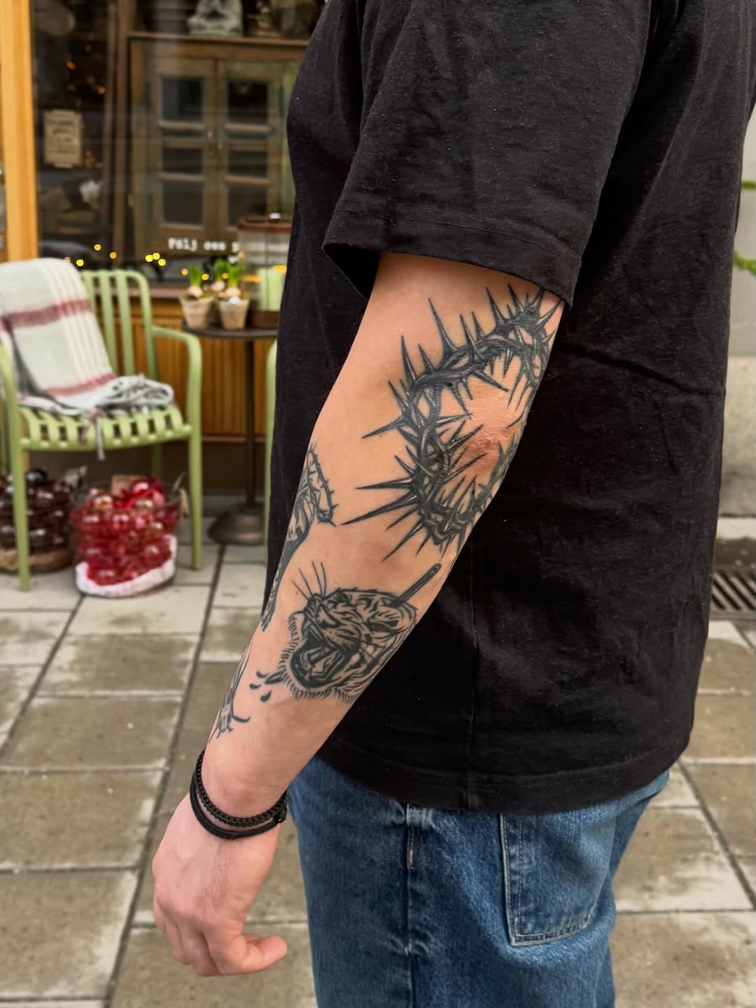 Bold blackwork forearm tattoo featuring barbed thorn ring and snarling beast