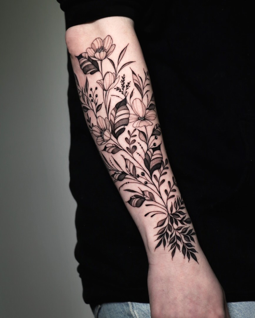 Intricate black floral forearm piece with bold linework