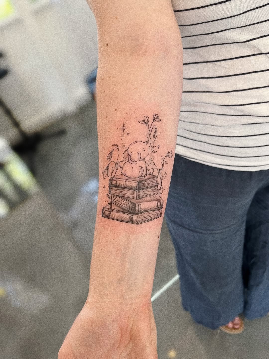 Whimsical fineline elephant perched on a vintage book stack.