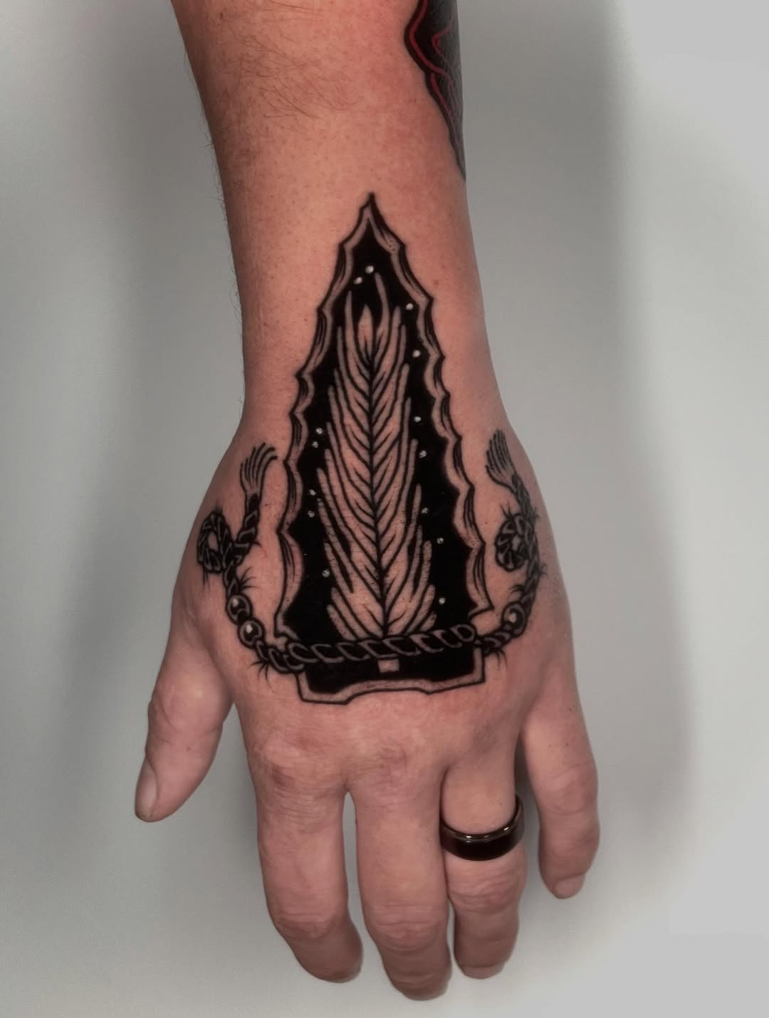 Bold blackwork ankle piece featuring shield-shaped leaf motif