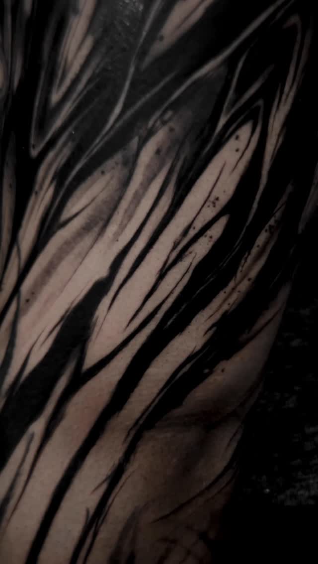 Bold blackwork forearm tattoo with flowing abstract linework