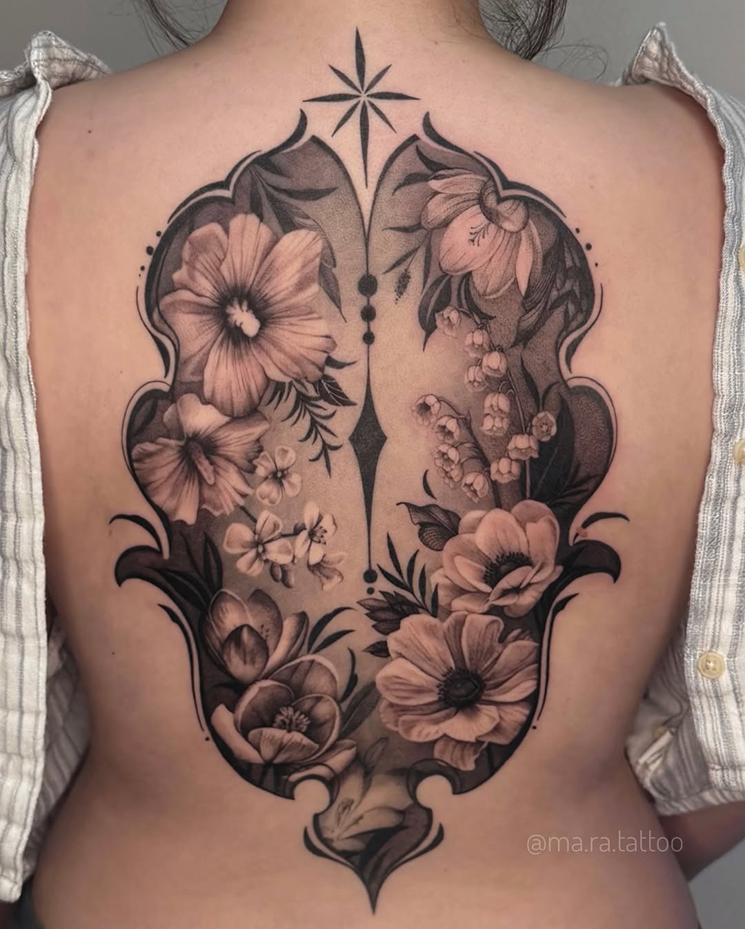 Intricate black-and-gray floral back piece within ornate shield