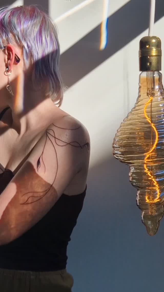 Delicate freehand linework shoulder tattoo with abstract leaves