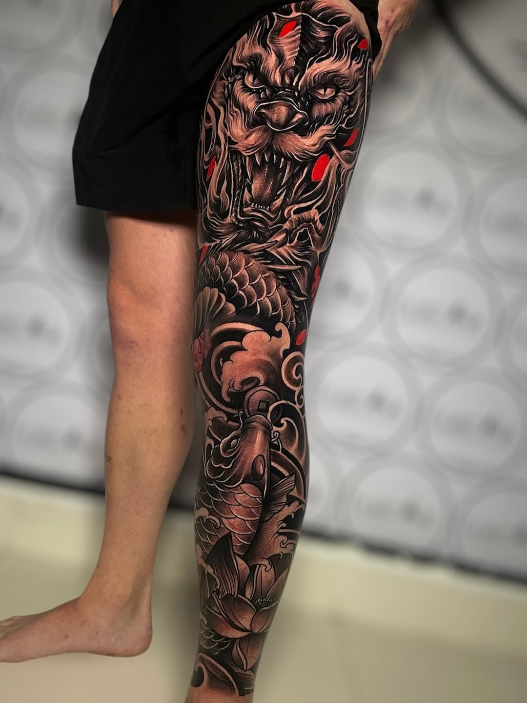 Ferocious black-and-gray dragon leg sleeve with red accents.