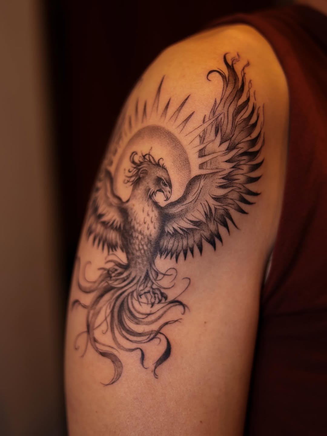 Dramatic blackwork phoenix with radiant rays and flowing swirls