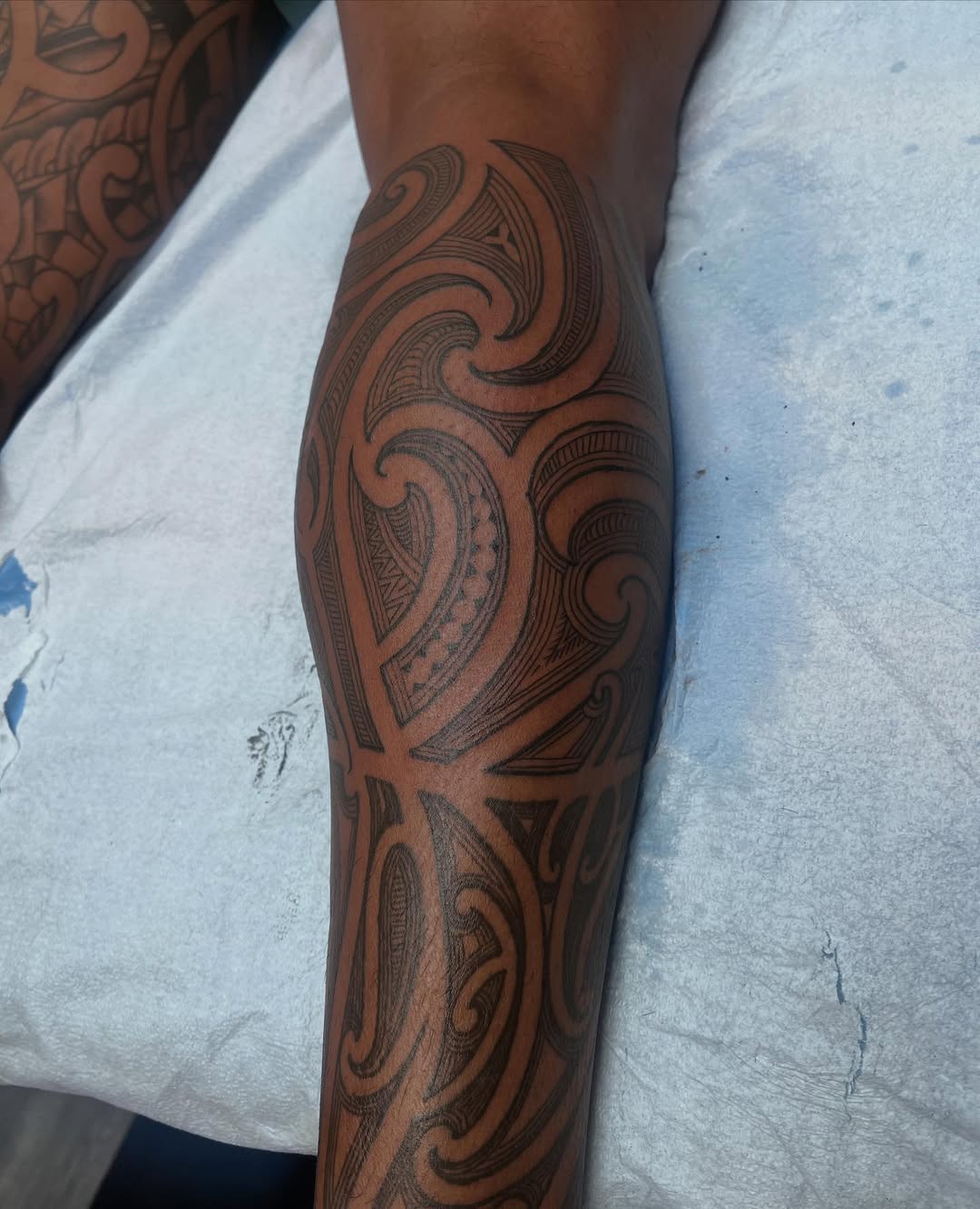 Maori ta Moko-inspired koru swirls in bold blackwork.