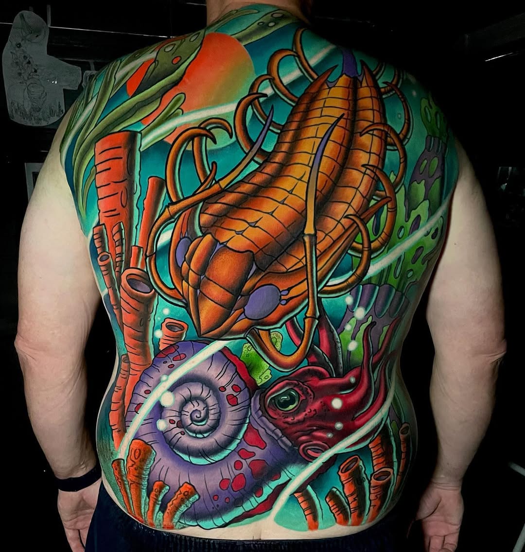 Vibrant neo-traditional underwater backpiece with lobster-like crustacean and ammonite