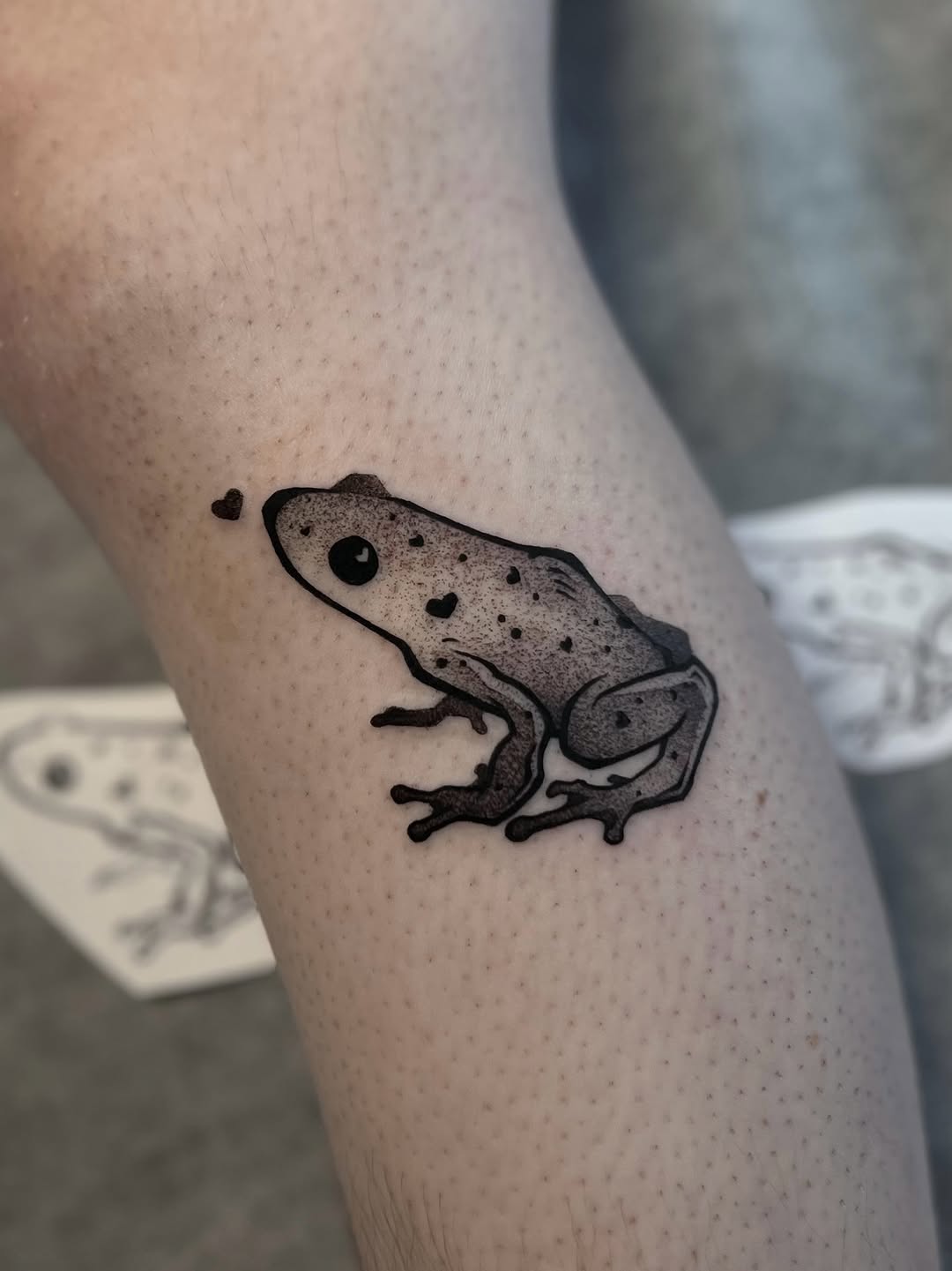 Tiny blackwork frog with dot shading on calf
