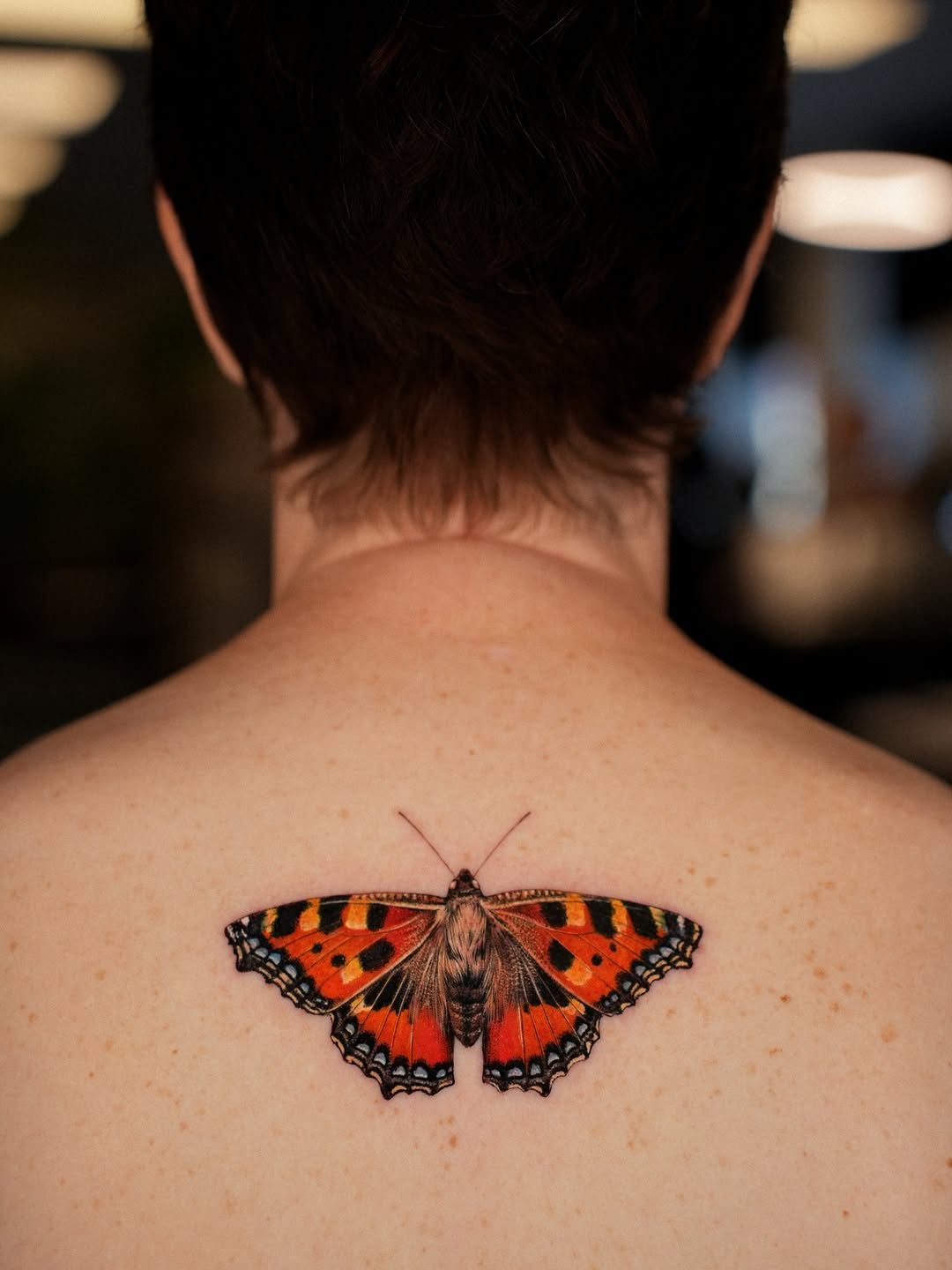 Vivid red-orange butterfly tattoo with black wing detail