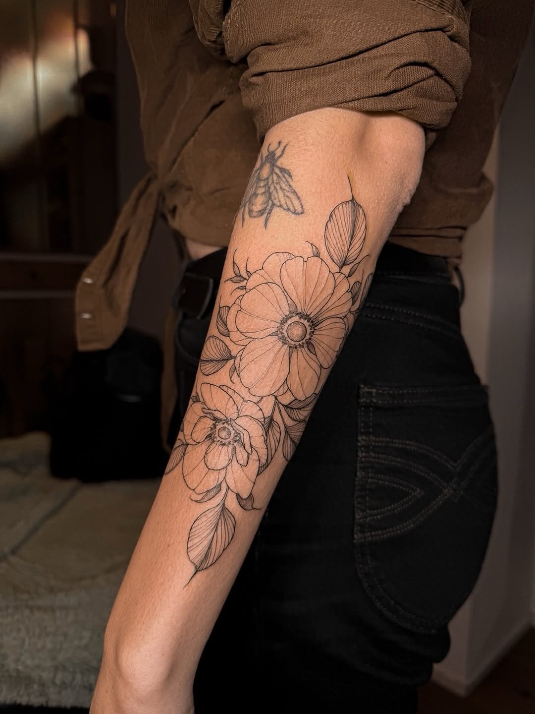 Bold-line anemone bouquet with clean linework along forearm