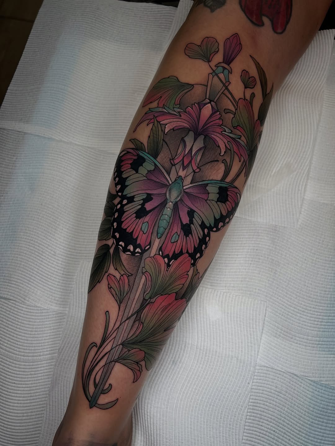 Vibrant neo-traditional butterfly with lush floral surround.