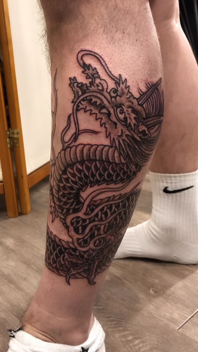 Intricate black dragon coils along the calf with bold scales.