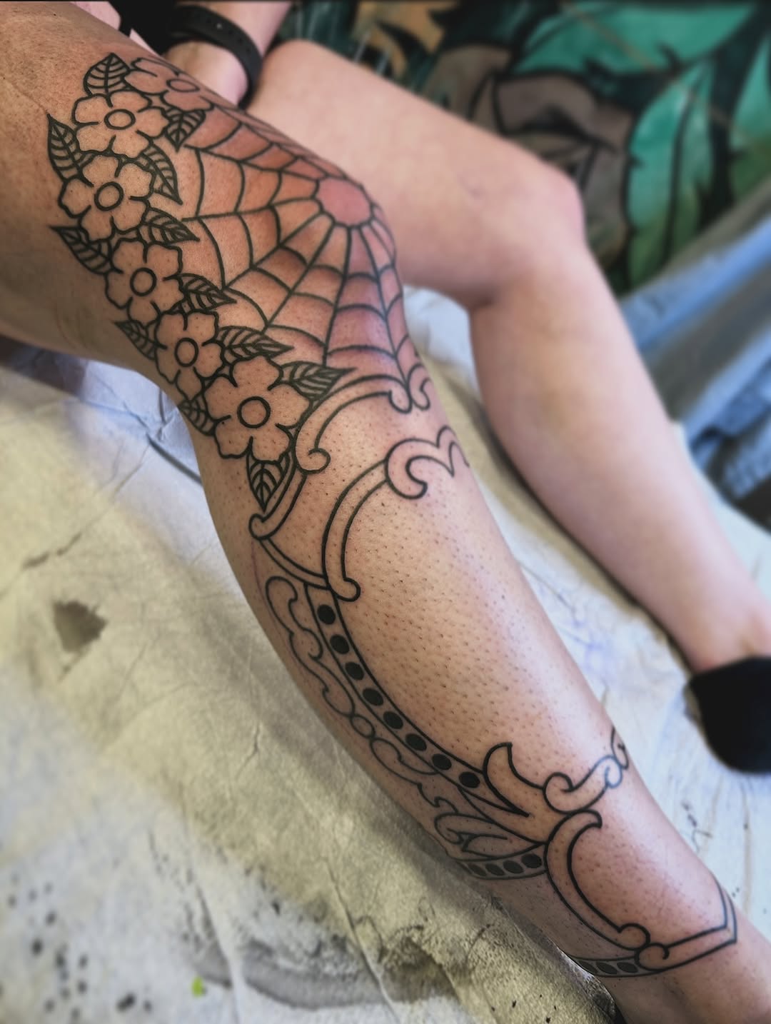Ornate floral-and-scrollwork leg sleeve with spiderweb motif