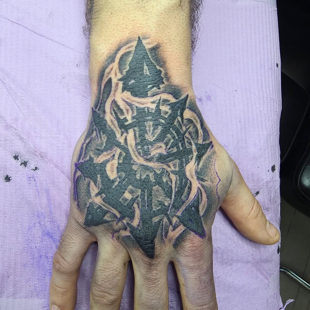 Bold black geometric chaos-star sprawls across the back of the hand