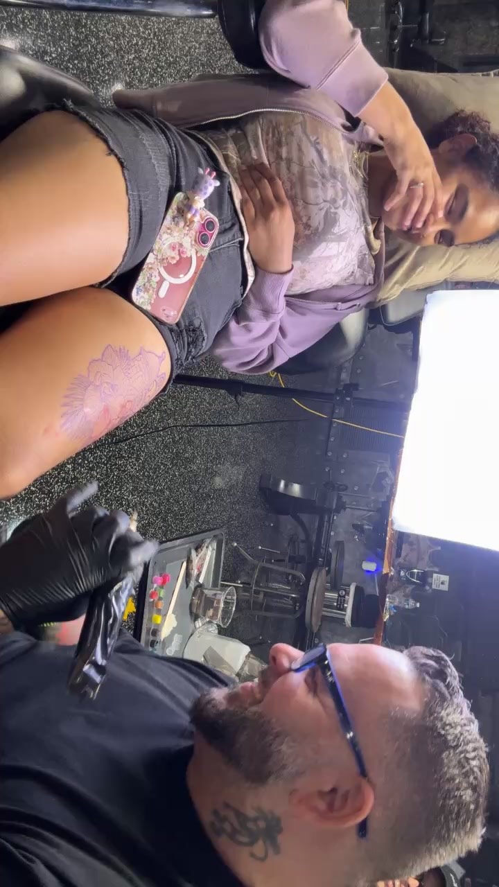 Delicate lavender floral thigh tattoo with fine linework