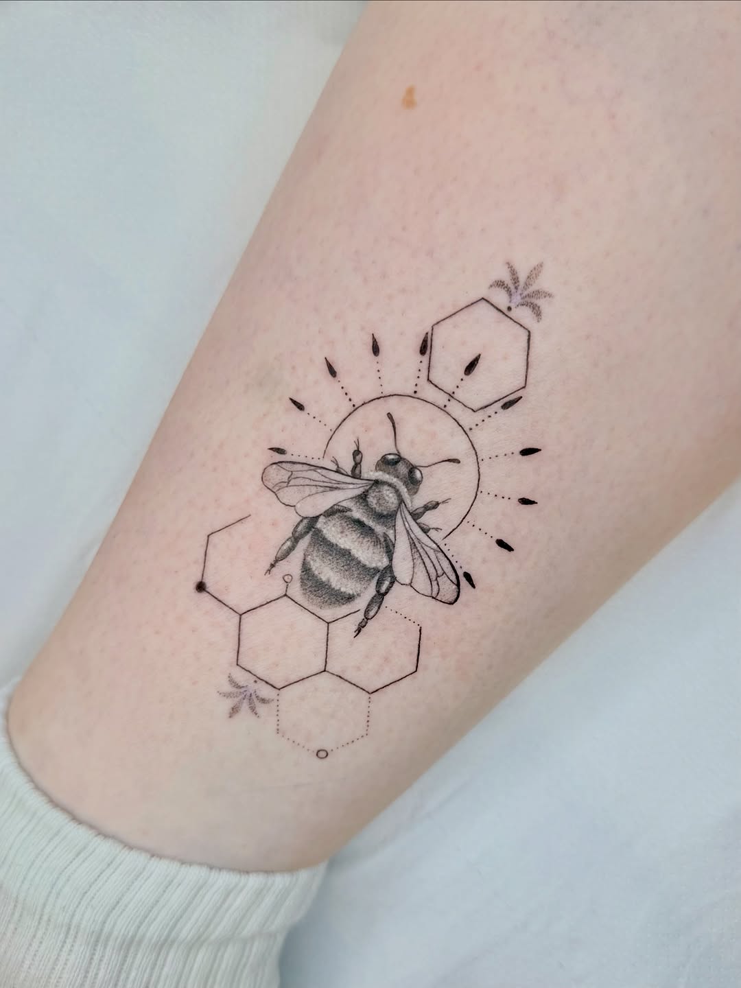 Delicate blackwork bee amid honeycomb and sunburst