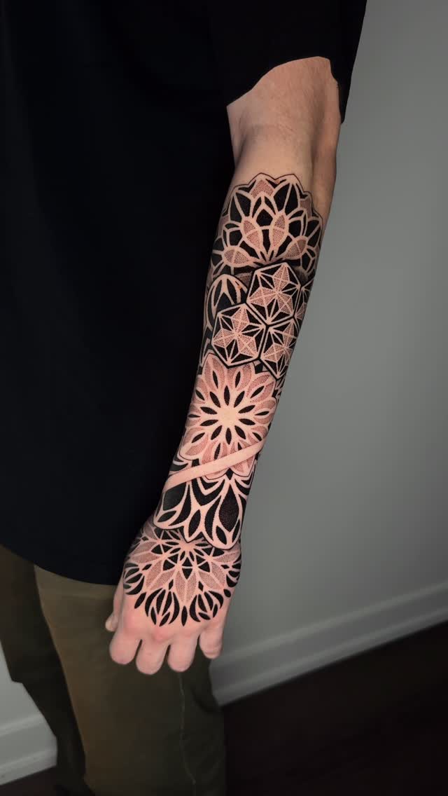 Intricate geometric mandala forearm piece with bold dotwork shading