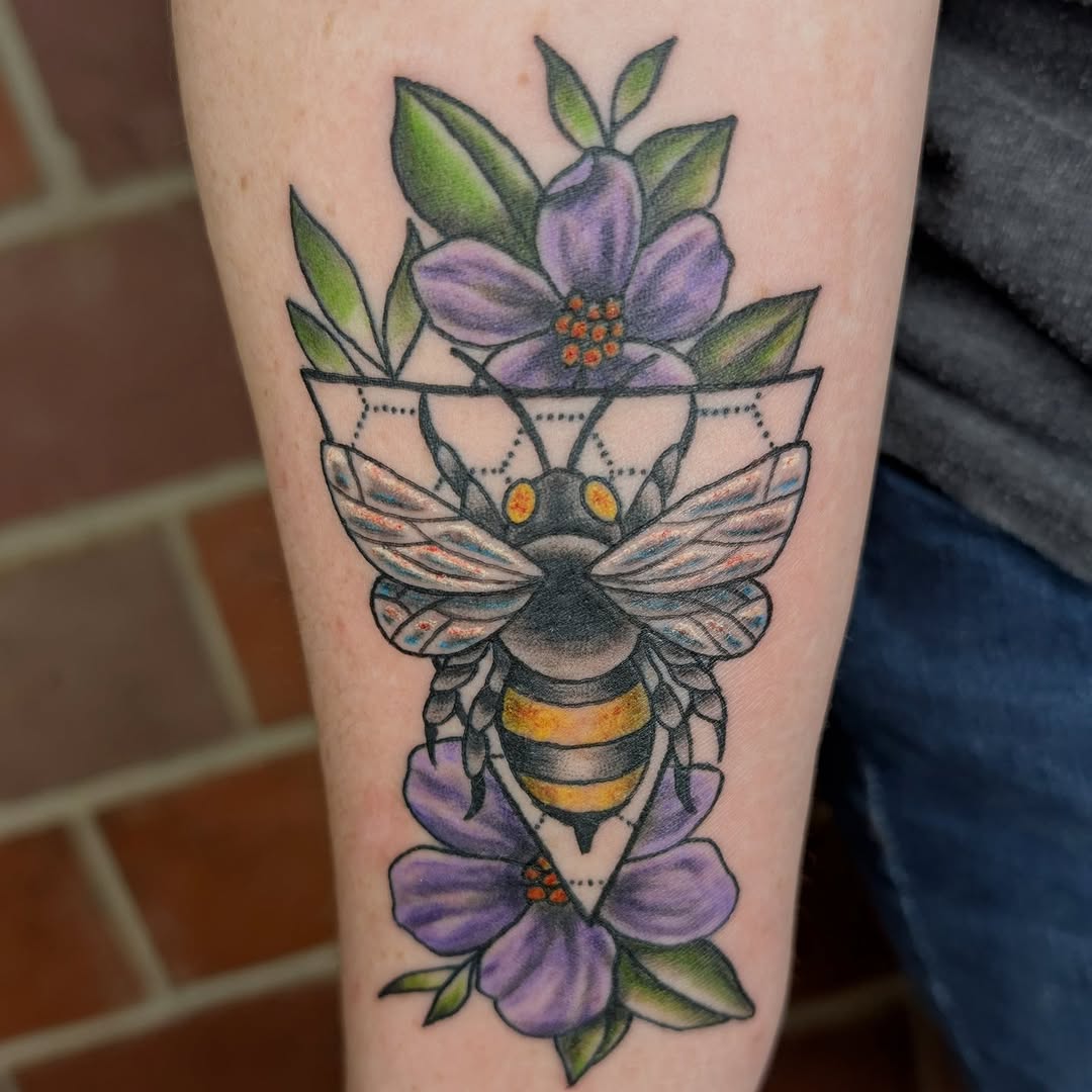 Bold neo-traditional bee with purple florals and geometric backdrop.