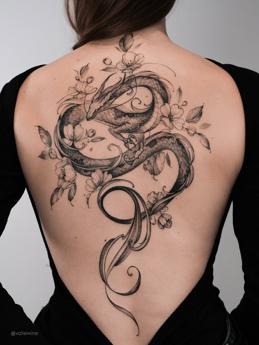 Graceful black dragon winding through blossoms with fine lines.