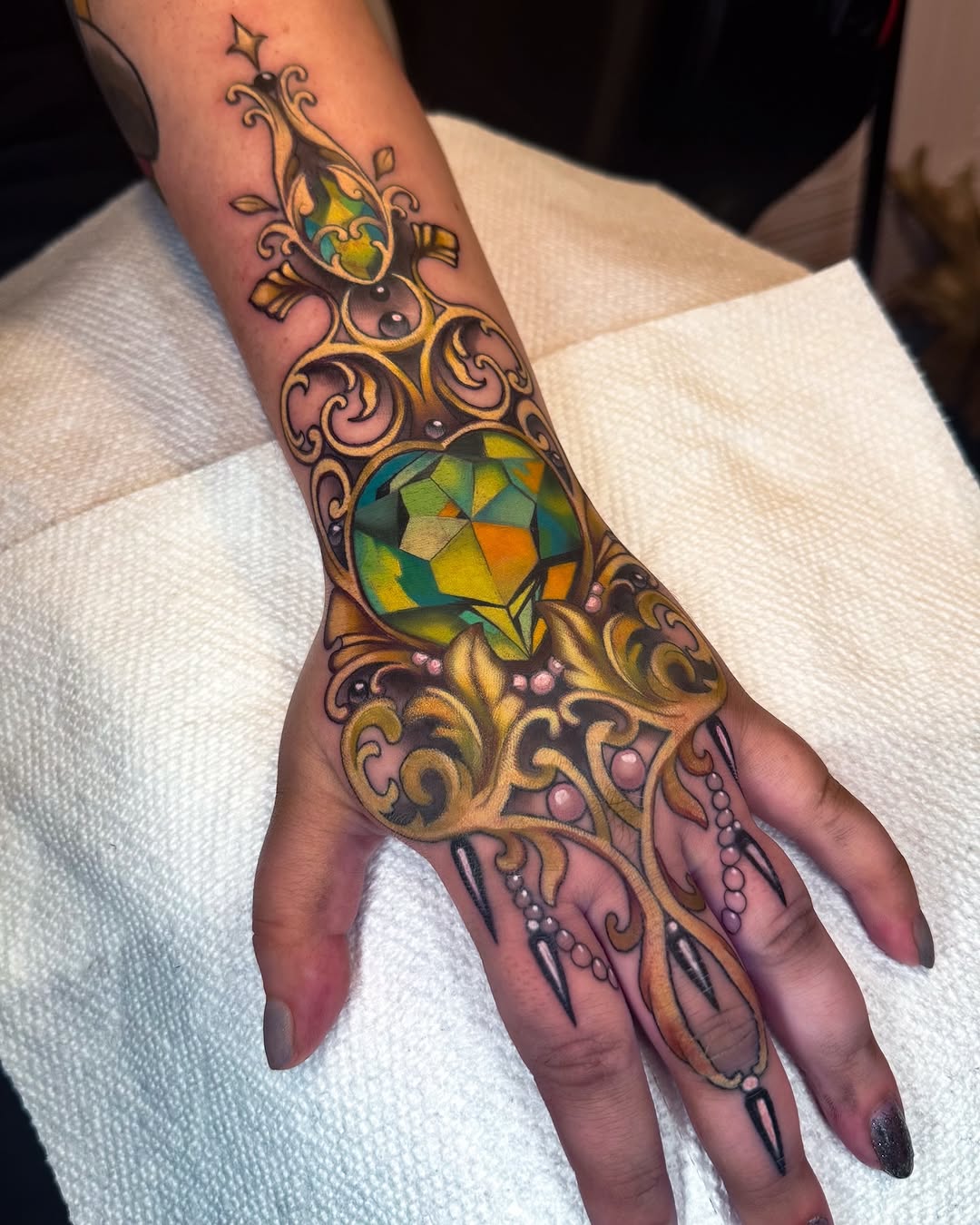 Opulent filigree hand tattoo with mosaic gem centerpiece