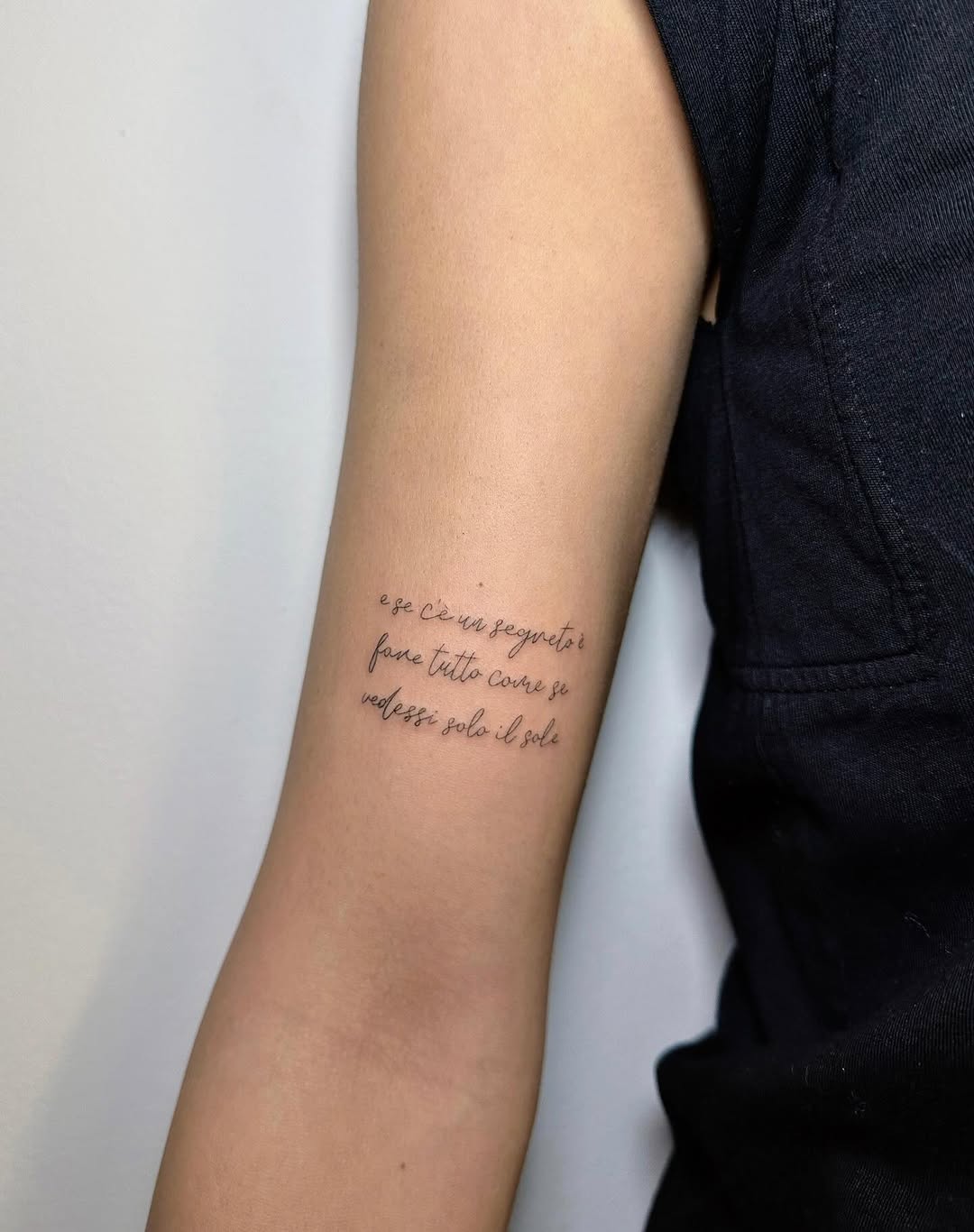Delicate fine-line script tattoo in Italian on inner forearm.
