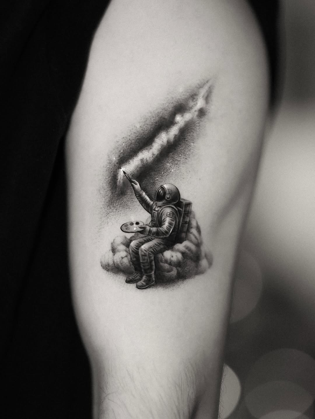 Dainty black-and-gray astronaut painting cosmic clouds.