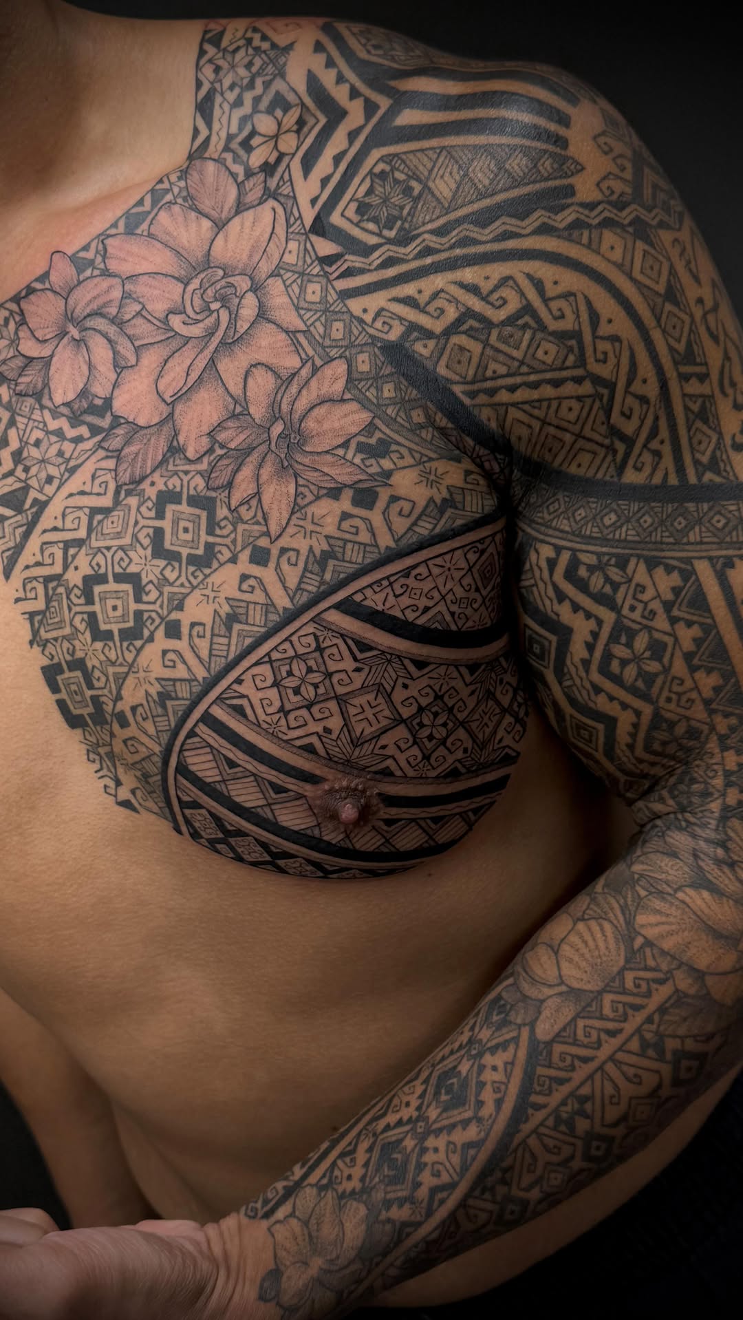 Polynesian-inspired blackwork chest piece with hibiscus florals