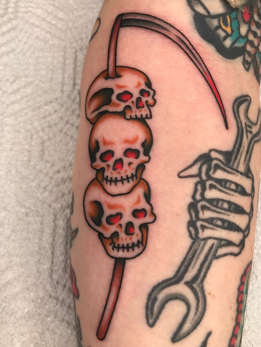 Bold traditional skulls stacked along a crimson thread