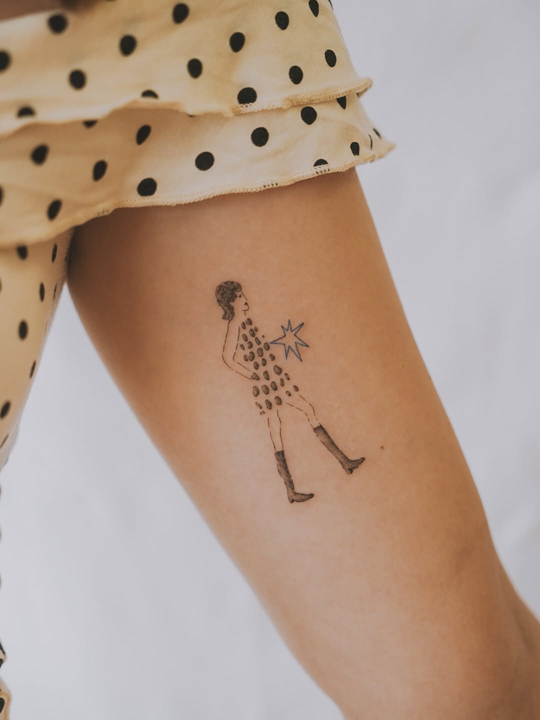 Minimalist dotted-dress figure with a star accent.