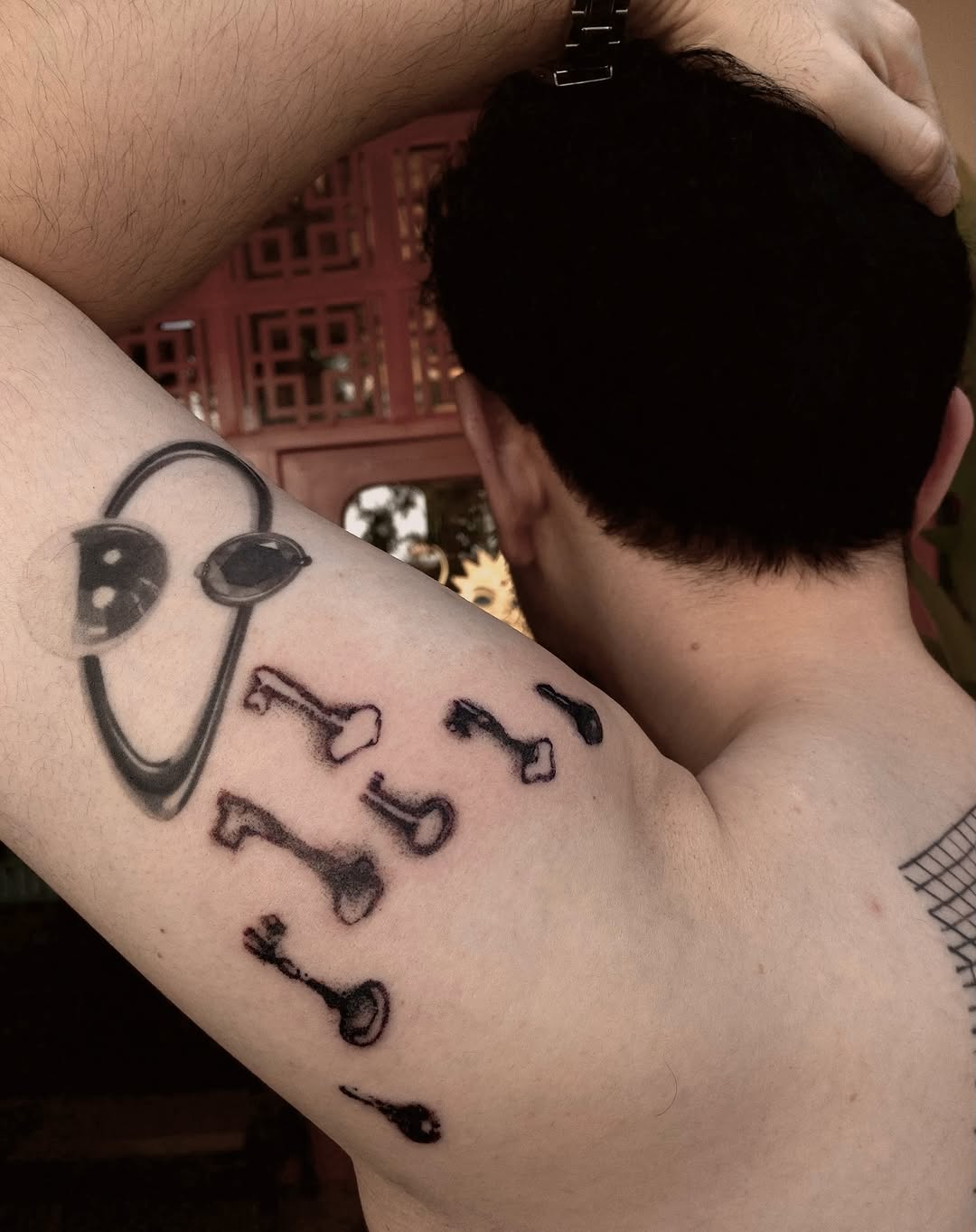 Bold black-line tattoo with circular goggles and bone fragments