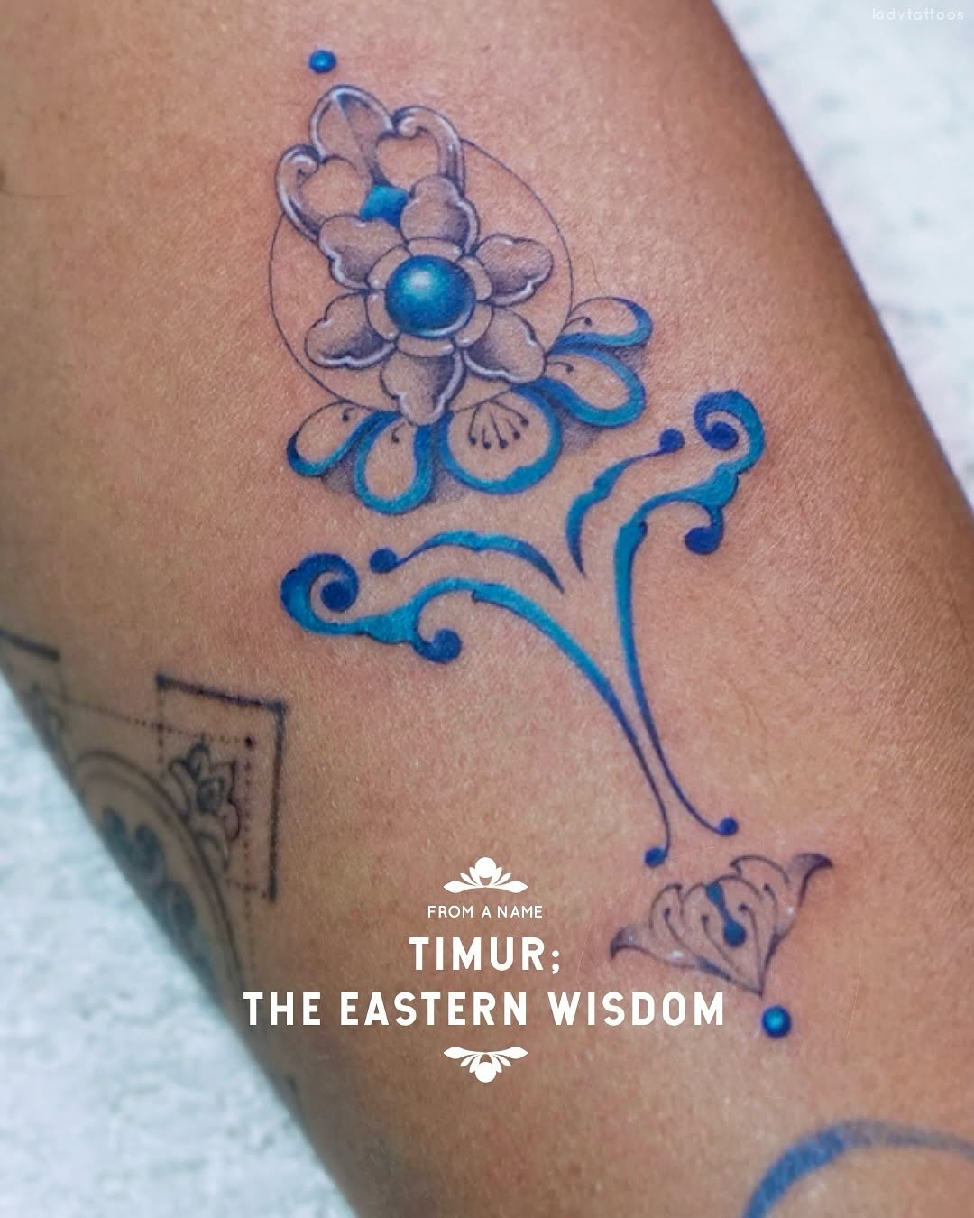 Delicate blue floral tattoo with elegant curling filigree