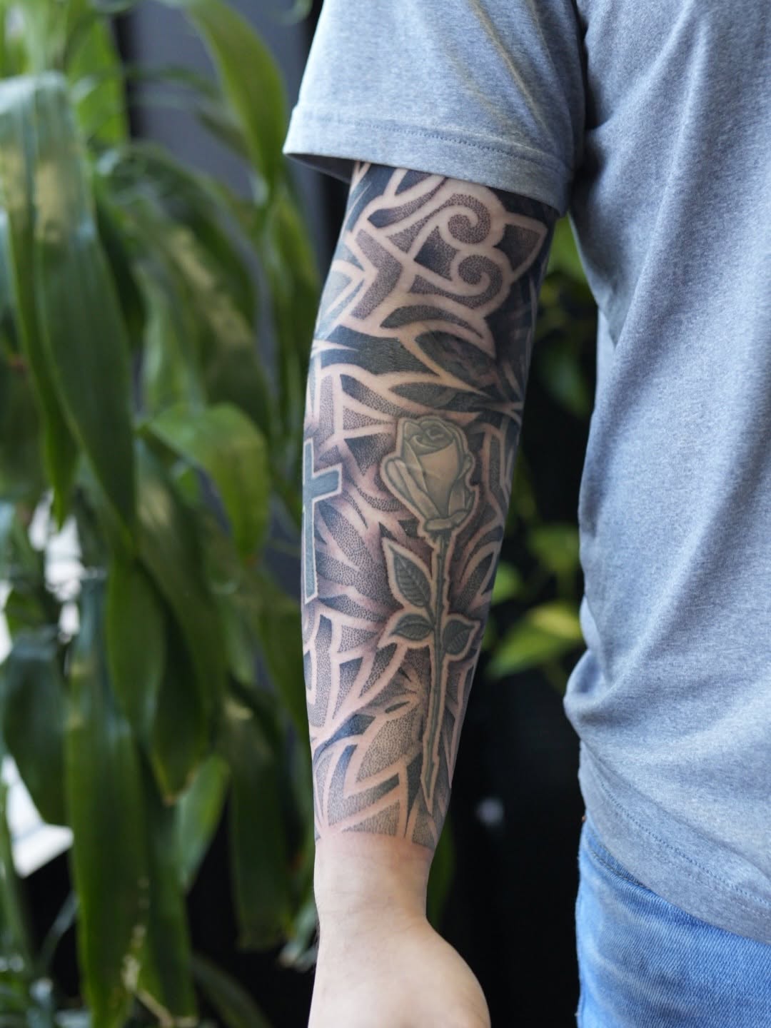 Intricate blackwork forearm sleeve with a rose motif and layered geometric patterns.