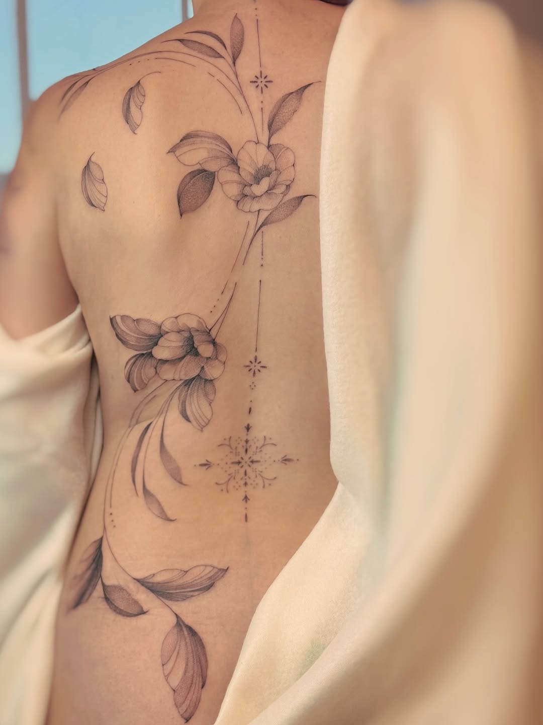 Delicate floral spine piece with slender vines and blossoms