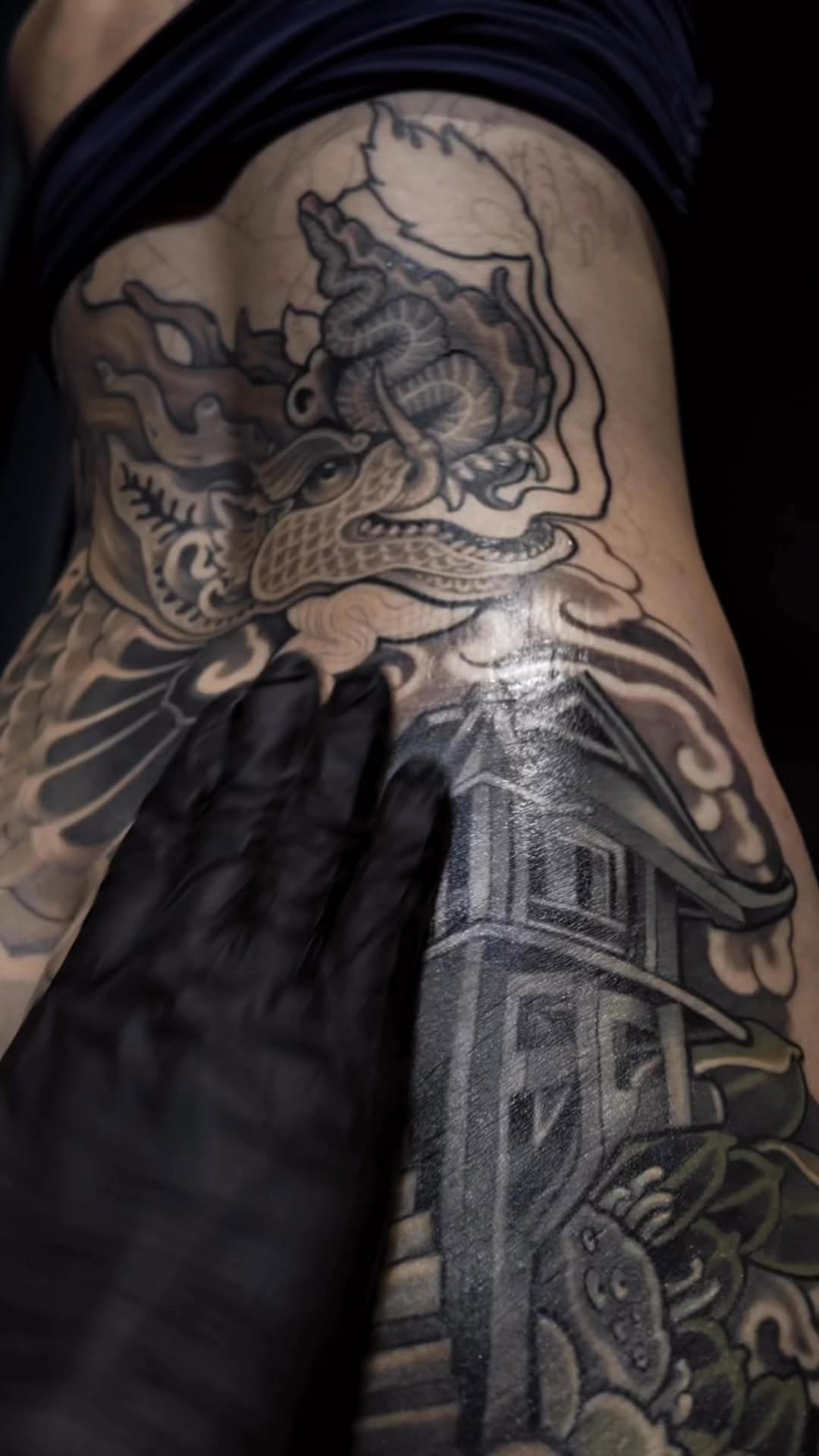 Intricate black-and-gray dragon entwined with waves and temple.