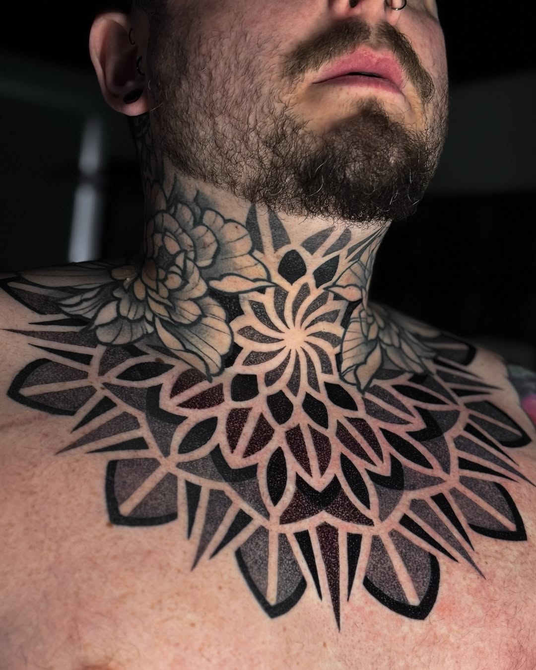 Bold blackwork mandala with radiating petals across neck.