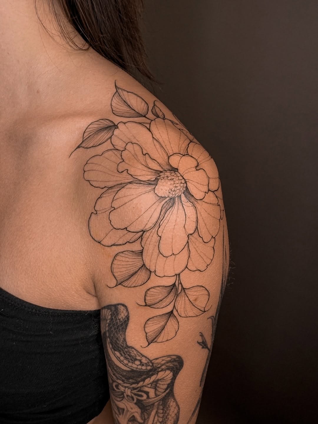 Delicate magnolia bloom with fine-line petals along shoulder