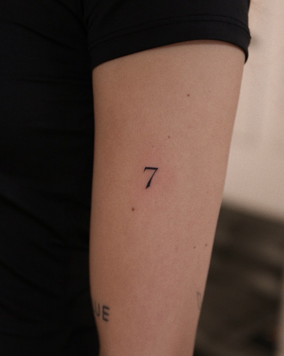 Delicate fine-line number seven on inner forearm.