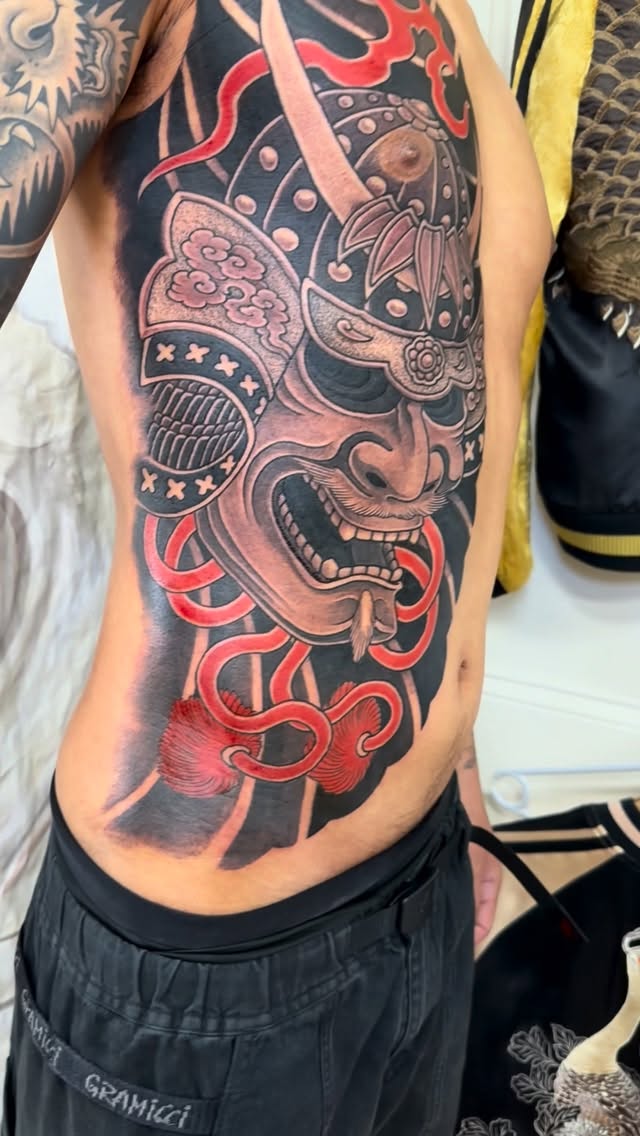 Fierce Japanese oni mask with bold black shading and red ribbons.