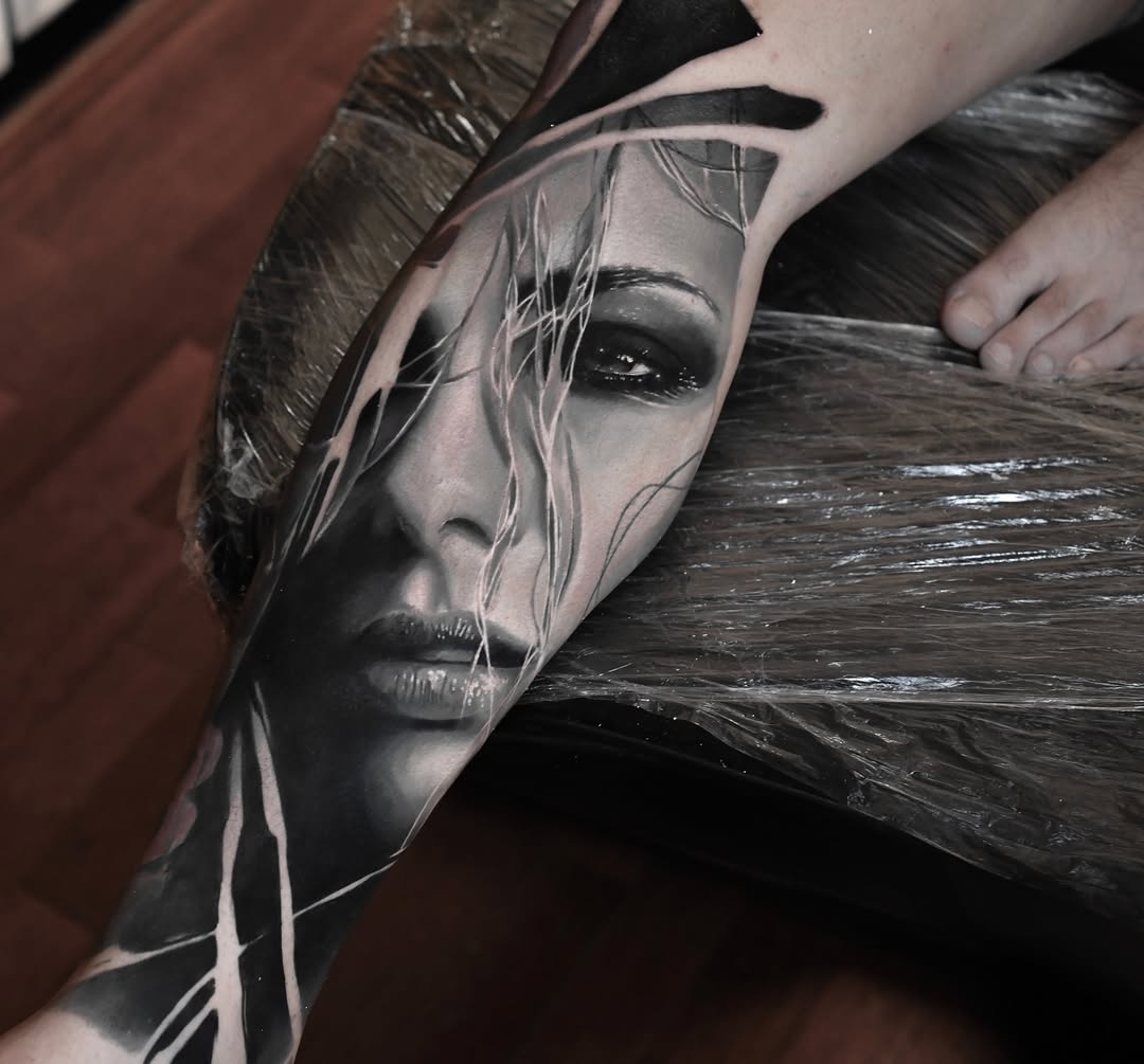 Hyper-realistic grayscale portrait on forearm with flowing strands