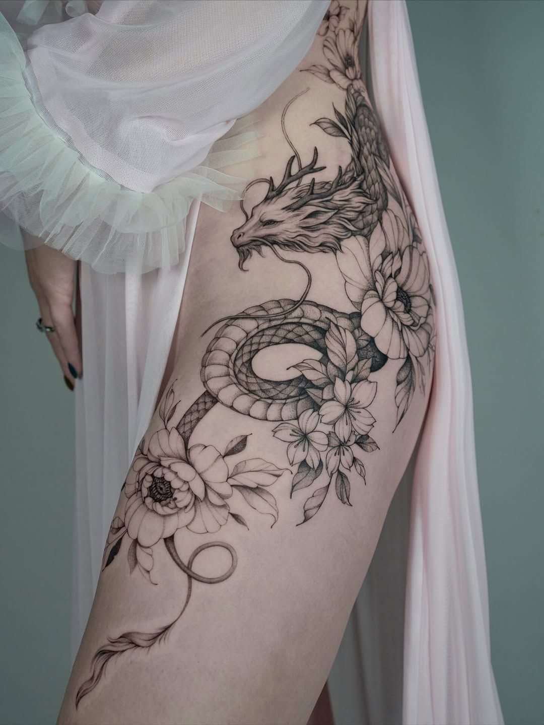 Bold black-line dragon winds through delicate floral vines.