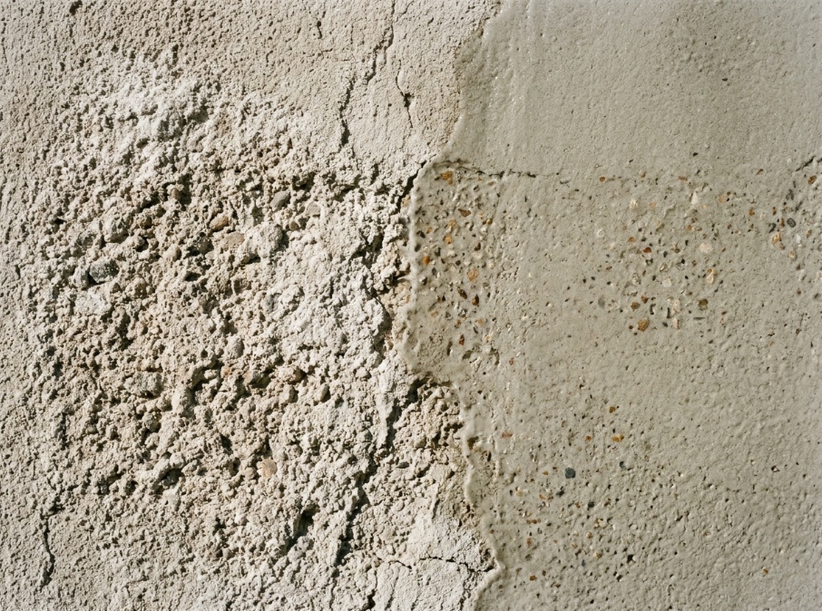 Chalky stucco wall partially treated with masonry sealer showing surface difference.
