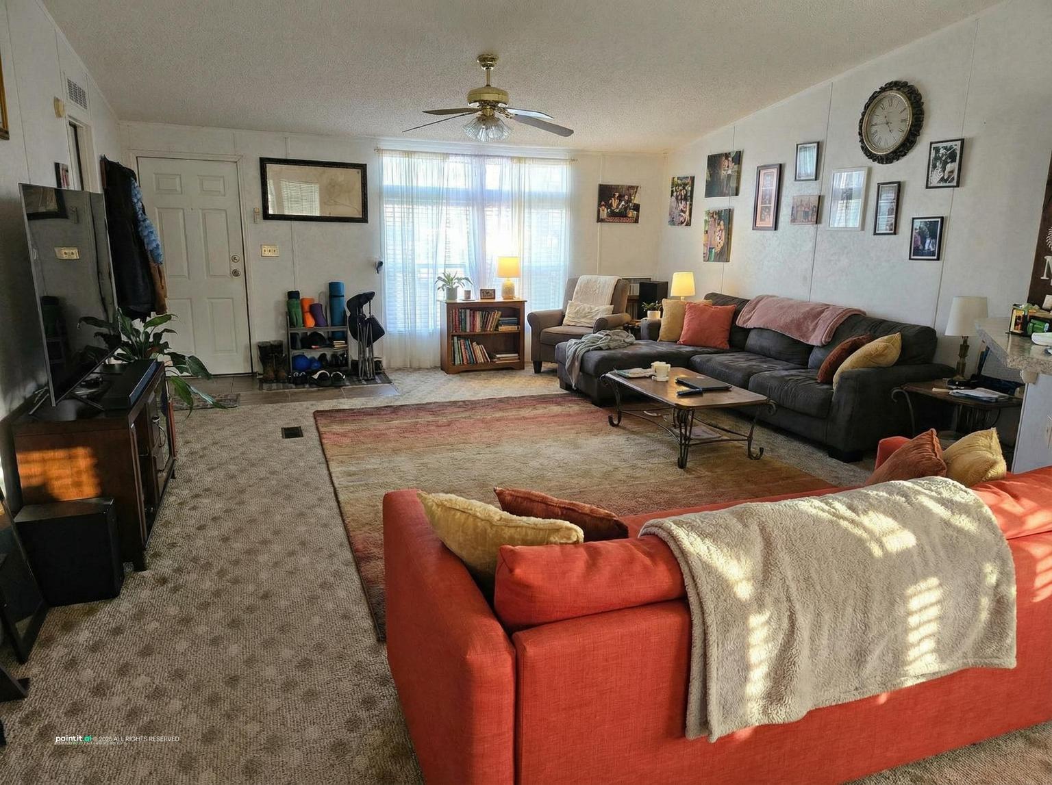 Living room with a red sofa, gray sofas, a patterned rug and a wall of clocks