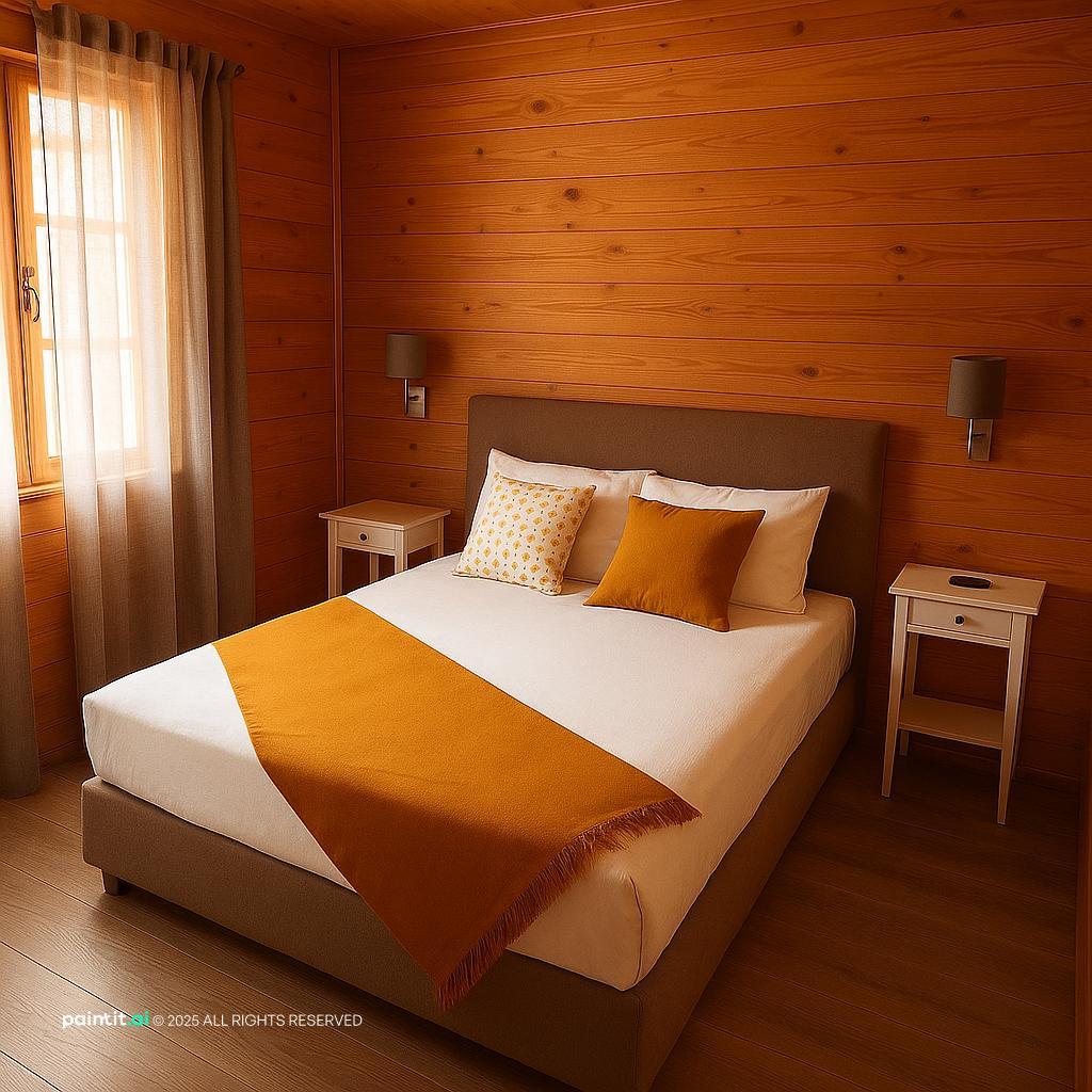 Small hotel room with warm wood-toned walls, white bedding with an orange throw and a white bedside table