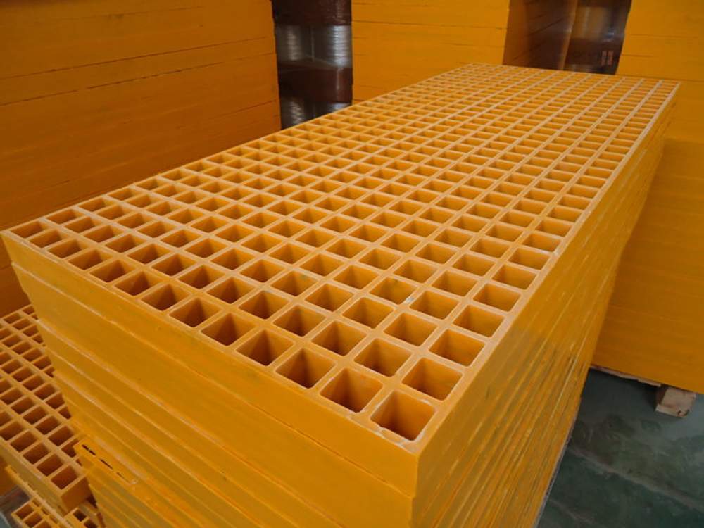 Stock of many standard-sized yellow molded fiberglass grating panels.
