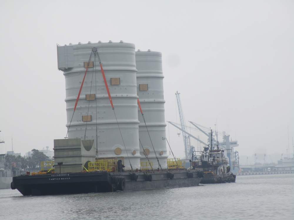 Two large fiberglass tanks (approx. 30 meters tall) being transported by sea.