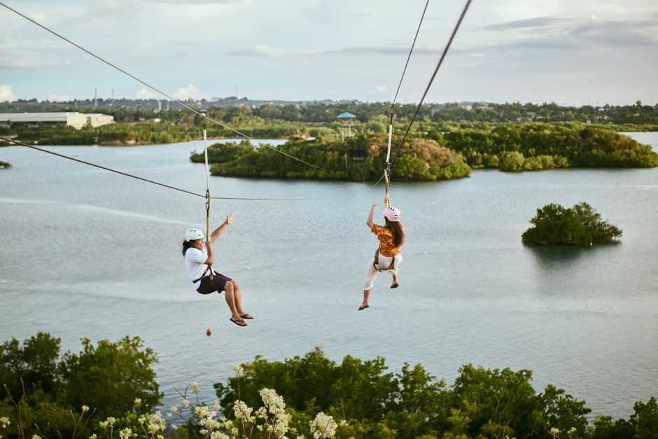 İki kişi sakin suların üzerinde zipline heyecanı yaşıyor