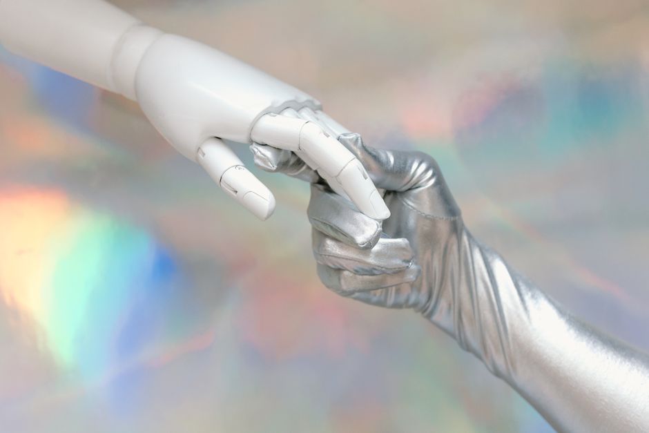 Close-up of a robot hand and silver-gloved hand touching